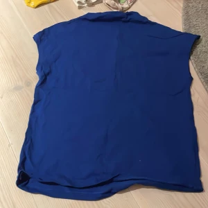 Blå topp från Lindex - Säljer en enkel och stilren blå topp från Lindex i storlek S. Perfekt för både vardag och festliga tillfällen. Toppen är i ett mjukt och bekvämt material.