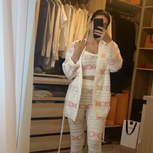 Vit stickad kofta med mönster - Supermysig vit stickad set med rosa mönster. Perfekt för kyliga dagar hemma. Den har långa ärmar och ett bälte i midjan för en bekväm passform. Nypris 829:-