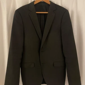 Svart kavaj från Esprit - Säljer en stilren svart kavaj från Esprit i mycket bra skick. Kavajen har en klassisk design med knappar och är tillverkad i ett bekvämt material. Är inte helt svart, utan har en brunaktig ton med ett annat material än de flesta kavajerna. Passar utmärkt till höst och vår. Storlek står ej, men jag gissar på medium+.