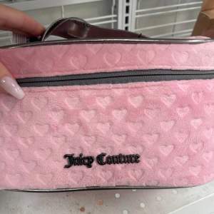 Superfin rosa necessär från Juicy Couture med hjärtmönster. Den har en dragkedja upptill och ett snyggt handtag i silverfärgat material. Perfekt för att förvara smink eller andra småsaker. Den är i nytt skick och redo att användas!