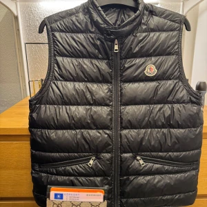 Moncler Gui storlek 3  - Moncler Gui Väst   -Storlek: 3  -Skick 9/10  -Nypris idag: 8999kr -Mitt pris: 3999kr.           Kvitto och tags medföljer självklart🙌🏻.           Tveka inte att höra av dig vid minsta frågan!
