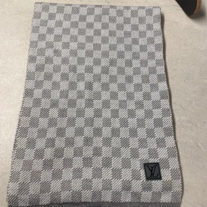 Grå rutig halsduk  - Säljer en elegant grå rutig halsduk  . Den är i mycket bra skick och har ett klassiskt  Perfekt för att hålla sig varm och stilren under kyliga dagar. Tillverkad i Italien med högkvalitativt material.