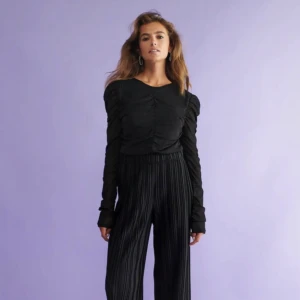 Svarta plisserade byxor - Säljer ett par svarta plisserade byxor i loose fit. De är högmidjade och perfekta för både vardag och fest. Byxorna har en elegant och flytande stil som ger en chic look. Passar bra till en enkel topp eller en mer dressad blus. Perfekta för höst och vår!