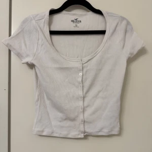 Vit ribbad topp från Hollister - Säljer en söt vit ribbad topp från Hollister. Toppen är i mycket bra skick och passar till både jeans och kjol. Superfin och enkel att matcha! 🌼