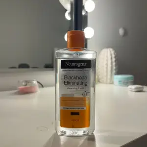 Säljer en flaska Neutrogena Blackhead Eliminating Cleansing Toner. Perfekt för att bekämpa pormaskar och hålla huden fräsch. Flaskan är genomskinlig med en orange etikett och lock. Perfekt för daglig användning för en klarare hud.