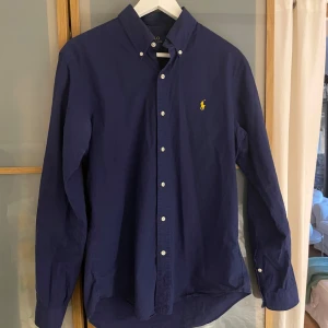 Marinblå skjorta från Ralph Lauren - Säljer en snygg mörkblå skjorta från Polo Ralph Lauren i slim fit. Skjortan har långa ärmar och knappar fram. Perfekt för både vardag och fest! 💙