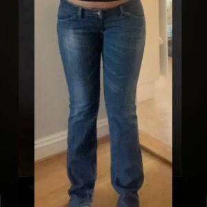 Blå lågmidjade bootcut jeans - Säljer ett par snygga blå bootcut jeans i bra skick. De har en klassisk femficksdesign med dragkedja på bakfickan för extra stil. 