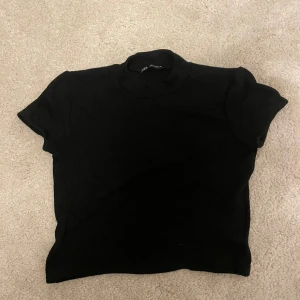 Svart t-shirt från Zara - Säljer en klassisk svart t-shirt från Zara i storlek XS. Perfekt basplagg för alla tillfällen. T-shirten är i bra skick och gjord av mjukt material som känns skönt mot huden. Passar både till vardags och fest. 🖤