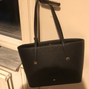 Handväska - En väska som jsg säljer för den inte kommer till användning. Jättebra skick då av att jag har använt den två gånger. Perfekt till skolan för det får plats med mycket. Köpt på zalando. Original pris ca 200