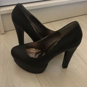Svarta pumps med klack - Säljer ett par eleganta svarta pumps från Gorgeous. De har en hög klack och en rundad tå, perfekt för festliga tillfällen. Skorna är i bra skick och har en stilren design som passar till många olika outfits.