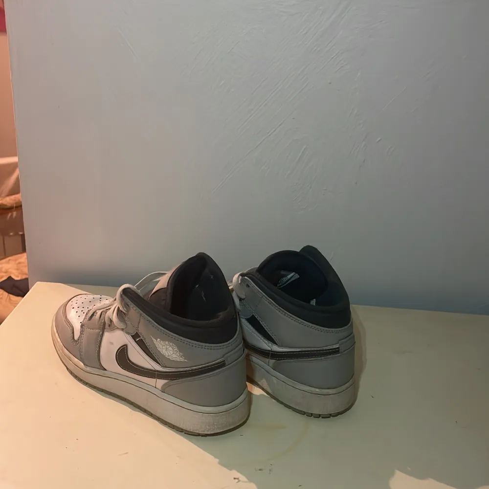 Säljer ett par Nike sneakers i grått och vitt. De har en klassisk design med snörning och en svart Nike-logga på sidan. Skorna är i bra skick och perfekta för vardagsbruk.. Skor.