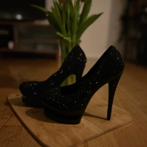 Sällsynta heels från Gianmarco Lorenz  - Säljer ett par eleganta och sällsynta svarta pumps med glittrig yta av Gianmarco Lorenz. . Perfekta för festliga tillfällen! De har en hög klack och en klassisk design som ger en snygg siluett. Skorna är i mycket bra skick och redo att användas för en kväll ute eller en speciell händelse.