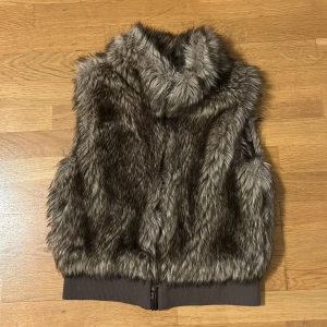 Brun pälsväst - Säljer en supermysig brun pälsväst från H&M i barnstorlek 164 men passar även super bra till xs eller S. Västen har en dragkedja framtill. Den är i mycket bra skick och har en mjuk insida. Tar emot prisförslag. (Inte riktig päls)