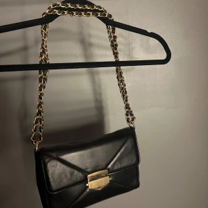 Handväska  - Svart axelremsväska med gulddetaljer. Fint skick 