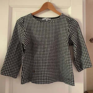 Svartvit rutig topp från Flash woman - Säljer en stilren svartvit rutig topp från Flash Woman.  Den har trekvartsärmar och en klassisk passform. Perfekt för både vardag och lite finare tillfällen. Det finns en liten fläck på framsidan, men annars i bra skick.