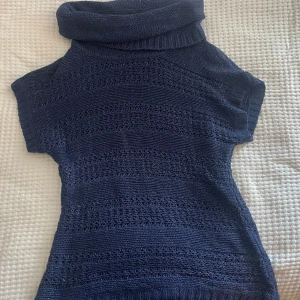 Mörkblå stickad polotröja från Isolde - Säljer en snygg mörkblå stickad polotröja från Isolde. Tröjan har en elegant polokrage och korta ärmar, perfekt för både höst och vinter. Den är i ett glittrigt material som ger en extra touch av stil. Passar perfekt till både vardag och fest!