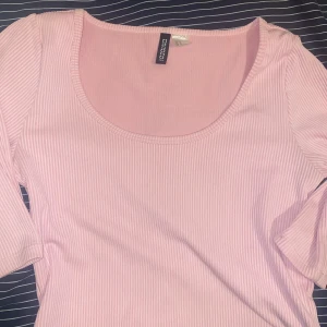 Rosa ribbad topp från Gina Tricot - Säljer en superfin rosa ribbad topp från H&M. Den har en rund halsringning och långa ärmar, perfekt för både vardag och fest. Toppen är i ett mjukt och stretchigt material som sitter bekvämt på kroppen.