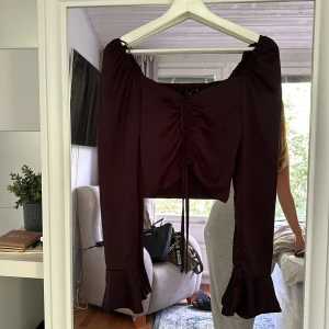 Topp  - Nytt skick, prislappen är kvar. Med snörena där fram kan man anpassa hur kort tröjan blir över magen. 