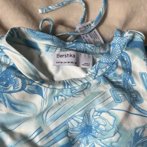 Crop top - Crop topp i superskönt material med coolt tryck på och en cut-out i ryggen. Har använt 1 gång🩵