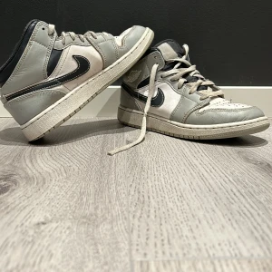 Grå och vita Nike sneakers - Säljer ett par grå och vita Nike sneakers i välanvänt skick. De har en klassisk design med snörning och den ikoniska Nike-loggan på sidan. Perfekta för  vardagsbruk eller träning. Nypris 3000 kr från hypestein i Stockholm.