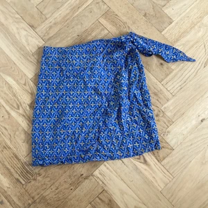 Blå omlottkjol - Säljer en blå och gul omlottkjol som är i storlek S men passar mig som är Xs. Fint skick