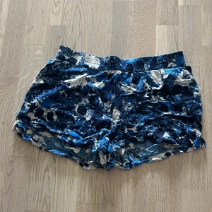 Blå camouflagemönstrade shorts - Säljer ett par blå camouflagemönstrade shorts. De är perfekta för sommarens alla äventyr och är både bekväma och stiliga. Passar bra till både träning och vardagsbruk. Shortsen har en elastisk midja för extra komfort.