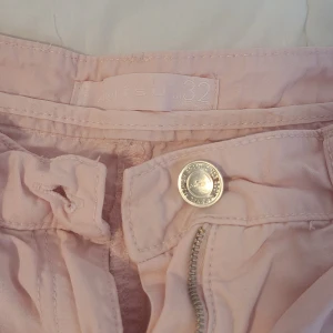 Ljusa rosa cargopants - Säljer ett par ljusa rosa cargopants i storlek 32. De har flera praktiska fickor och kan sjusteras längst ned på byxorna. Använda en gång. Som nya, inga fläckar eller hål.