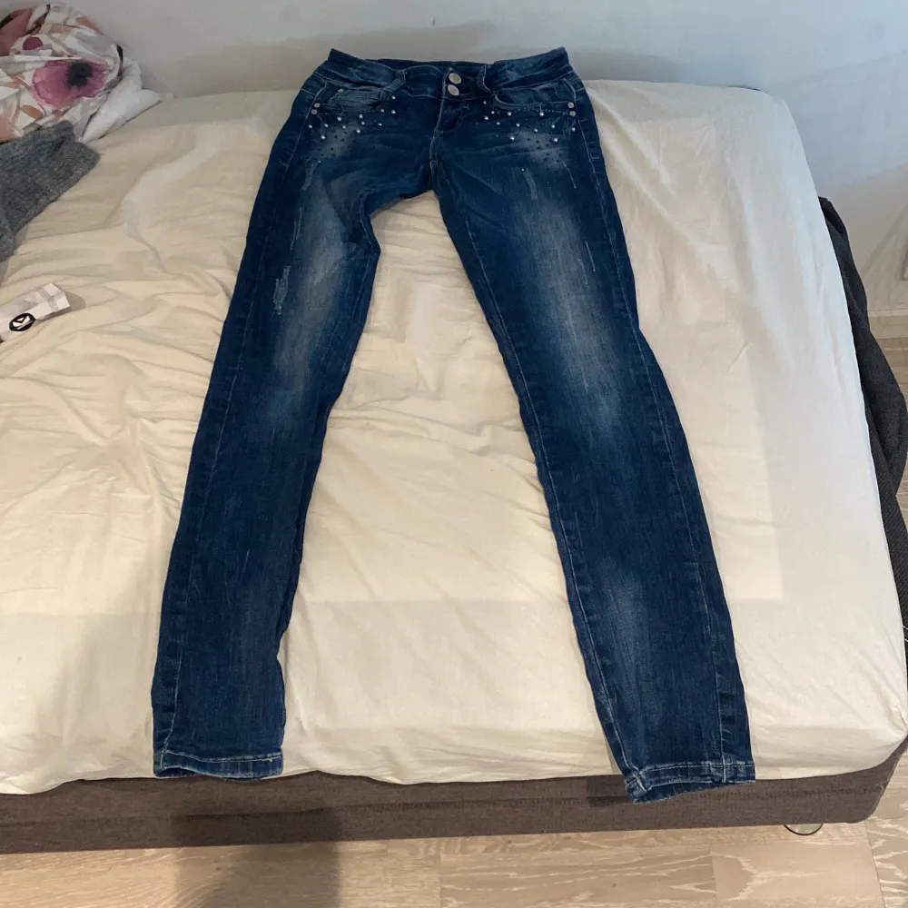 Säljer ett par snygga blå skin jeans från Mirelle i storlek 26 men passar tjej med Xs-S. De har coola pärldetaljer vid fickorna och en bekväm passform. Perfekta för både vardag och fest! 🥳. Jeans & Byxor.