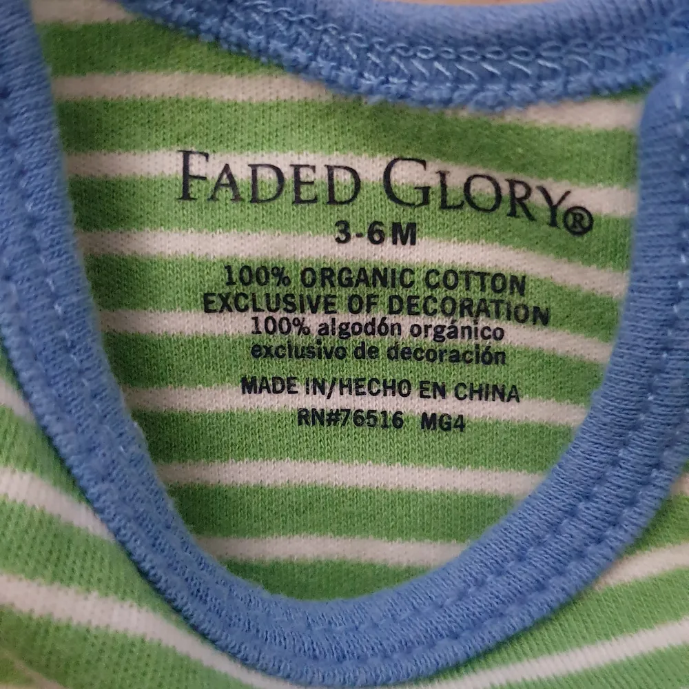 Söt liten t-shirt för de minsta från Faded Glory. Den är grön- och vitrandig med blå kant vid halsen. Tillverkad i 100% ekologisk bomull, perfekt för sommarens varma dagar. Passar både till lek och vila.. T-shirts.