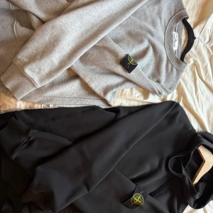 Stone island  - Säljer två stone island plagg. En grå sweatshirt i perfekt skick. Inga defekter. Alltid tvättad för hand. Sedan en svart hoodie också i prefekt skick. Luvan krympte pyttelite i tvätten men annars också perfekt skick. Kvitto finns online då de är beställda från en hemsida med namn LUISAVIAROMA. 1300 (grå). 1250 (svart). Paketpris (2000)