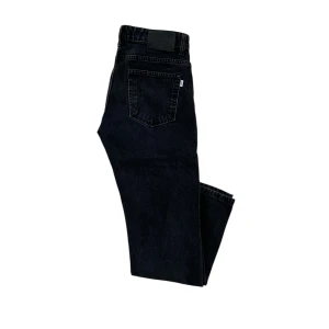 Svarta jeans från Woodbird - Säljer ett par snygga svarta jeans från Woodbird i storlek 28/32. De har en klassisk femficksdesign och är perfekta för både vardag och fest. Jeansen är i bra skick och har en stilren look som passar till det mesta. Perfekt för dig som vill ha en tidlös stil!
