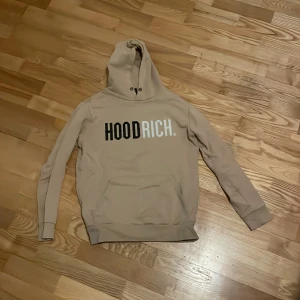 Beige hoodie från Hoodrich - Säljer en snygg beige hoodie från Hoodrich i storlek xs men passar s och m  Den har en stor logga på framsidan i svart och vitt. Perfekt för höst och vår med sin mjuka och bekväma passform. Huvan har snörning och muddar vid ärmslut och nederkant för extra komfort.