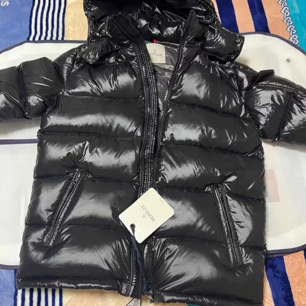 Säljer en snygg svart dunjacka från Moncler i nytt skick. Jackan har en glansig finish och är perfekt för vintern. Den har en dragkedja framtill och en huva för extra värme. Perfekt för kalla dagar! 🖤. Jackor.