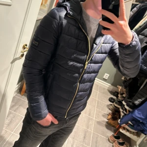 Svart pufferjacka från Polo Club - Säljer en snygg mörkblå pufferjacka från Polo Club i storlek M men passar S också. . Perfekt för höst och vinter med sin quiltade design och huva. Den är i mycket bra skick, då jag inte använt den så mycket.