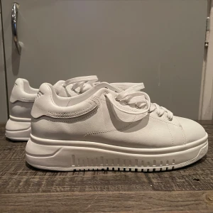 Vita sneakers från Armani - Snygga vita sneakers från Armani i nytt skick. De har en stilren design med snörning och en diskret logga på hälen. Perfekta för både vardag och fest. Skorna är aldrig använda. Nypris 3000kr och mitt pris går att diskutera😅