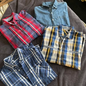 Fyra rutiga skjortor i olika färger - Säljer fyra snygga rutiga skjortor i olika färger. En röd och blå, en blå och vit, en gul och blå, och en ljusblå jeansskjorta. Perfekta för både vardag och fest! Alla skjortor har långa ärmar och knappar framtill. De är i jätte bra skick och redo för nya äventyr. Passar perfekt till jeans eller chinos!