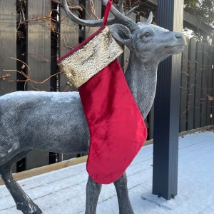 Röd julstrumpa med guldpaljetter - Snygg och festlig röd julstrumpa i sammet med en glittrig kant av guldpaljetter. Perfekt att hänga upp vid spisen eller på väggen för att skapa julstämning. Strumpan har en praktisk ögla för enkel upphängning. Perfekt för att fylla med små julklappar eller godis! Nypris 159:-