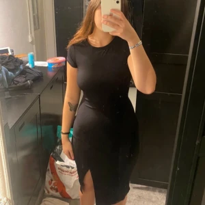 Svart tight klänning med slits - Säljer en snygg svart klänning i tight passform. Den har korta ärmar och en stilren slits framtill. Perfekt för både vardag och fest! 🖤Går ner till knäna och är stretchig 