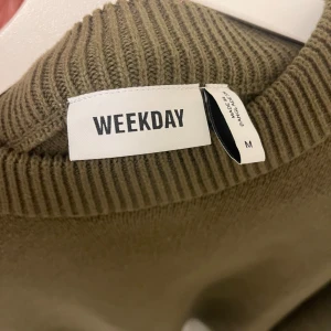 Olivgrön stickad tröja från Weekday - Säljer en olivgrön stickad tröja från Weekday i storlek M. Tröjan har en klassisk design med ribbad krage och långa ärmar. Perfekt för höst och vinter för en stilren och bekväm look. 🧶