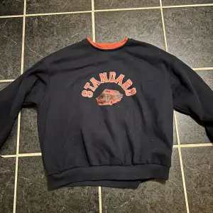 Cool mörkblå sweatshirt från Shein med trycket 'STANDARD' och en bil på framsidan. Den har en kontrasterande orange krage som ger en extra touch. Perfekt för en avslappnad stil och passar bra till jeans eller joggers. Skön och bekväm för vardagsbruk!