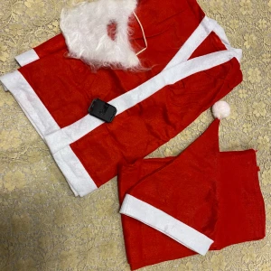 Barn Tomtedräkt med skägg - Säljer en klassisk tomtedräkt i röd och vit färg. Dräkten inkluderar en röd kappa med vita kanter och ett matchande skägg. Perfekt för julfirandet! 🎅 passar 4-8 år 