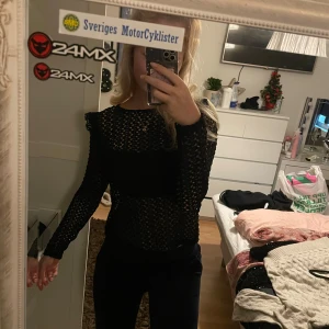 Svart spetsblus - Säljer en elegant svart spetsblus med långärmad design i storlek S. Perfekt för en utekväll eller fest. Blusen har ett vackert mönster och är i mycket bra skick. Passar bra till både jeans och kjol för en stilren look.