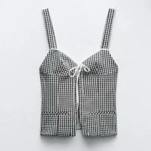Rutig korsett topp - Snygg svartvit rutig topp med smala axelband och söt knytning framtill. Perfekt för sommardagar och ger en chic look. Toppen har en figurnära passform och är superbekväm att bära. Har prislappen kvar 