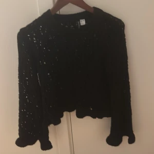 Slutsåld hm stickad  - Säljer en svart stickad tröja med ett unikt hålmönster. Tröjan är långärmad och har en croppad passform, perfekt för lager på lager-stil. Den är både stilren och bekväm, idealisk för höst och vinter. Passar bra till både jeans och kjol!