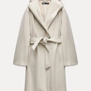 Beige kappa från Zara - Säljer en superfin beige kappa från Zara i storlek XS. Den har en elegant knytning i midjan och en stor huva som ger en mysig känsla. Perfekt för höst och vinter! Kappan är i mycket bra skick och passar både till vardags och fest.