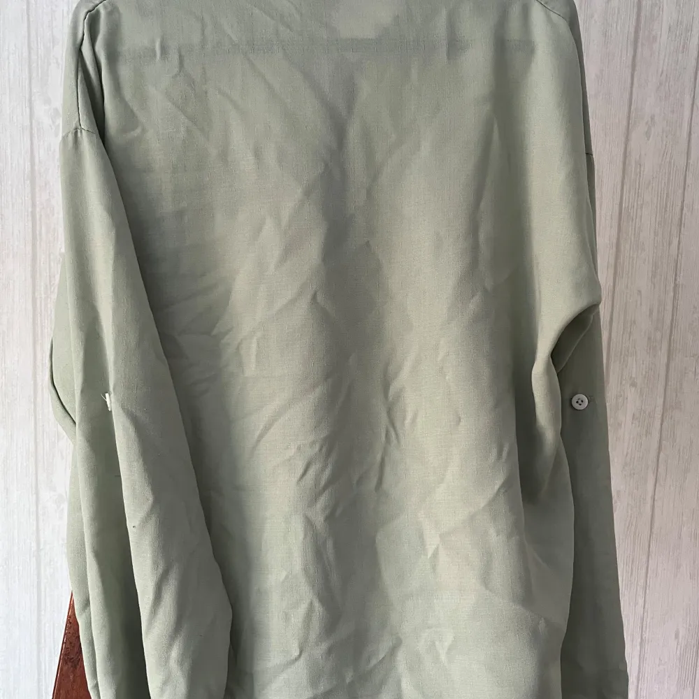 Snygg grön skjorta i en mix av polyester och bomull. Skjortan har långa ärmar och knappar framtill samt en bröstficka. Perfekt för en avslappnad stil.. Puserot.