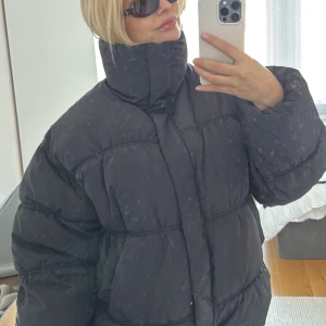 Svart pufferjacka - Säljer en svart pufferjacka med hög krage och dragkedja. Jackan är perfekt för kyliga dagar och har en oversized passform! Köpt för en vecka sen. 