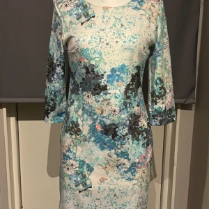 Blommig klänning från H&M - Snygg blommig klänning från H&M med trekvartsärm och ett färgglatt mönster i blått, grönt och svart. Perfekt för en färgglad look.