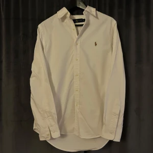 Vit skjorta från Ralph Lauren - Klassisk vit skjorta från Ralph Lauren med broderad logotyp på bröstet.  Skjortan är knappt använd och är i perfekt skick. Storleken är S men skulle säga att den passar M också. Kontakta gärna vid frågor ☺️