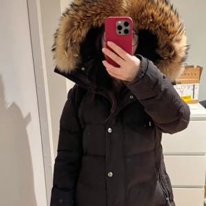 Svart dunjacka med päls - Svart dunjacka med stor huva och pälsdetaljer. Perfekt för kalla vinterdagar. Hollies Subway modellen, säljs pga för liten. Några minimala defekter i övrigt mycket fint skick. 